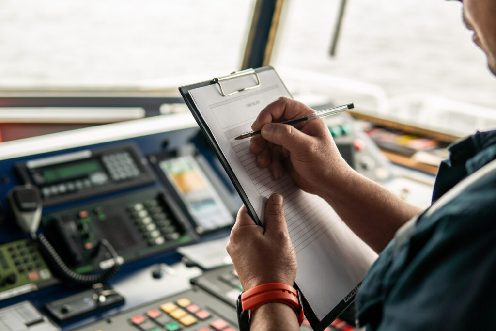 Image of a person standing at boat controls holding a clipboard that says "checklist"