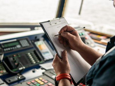 Image of a person standing at boat controls holding a clipboard that says "checklist"